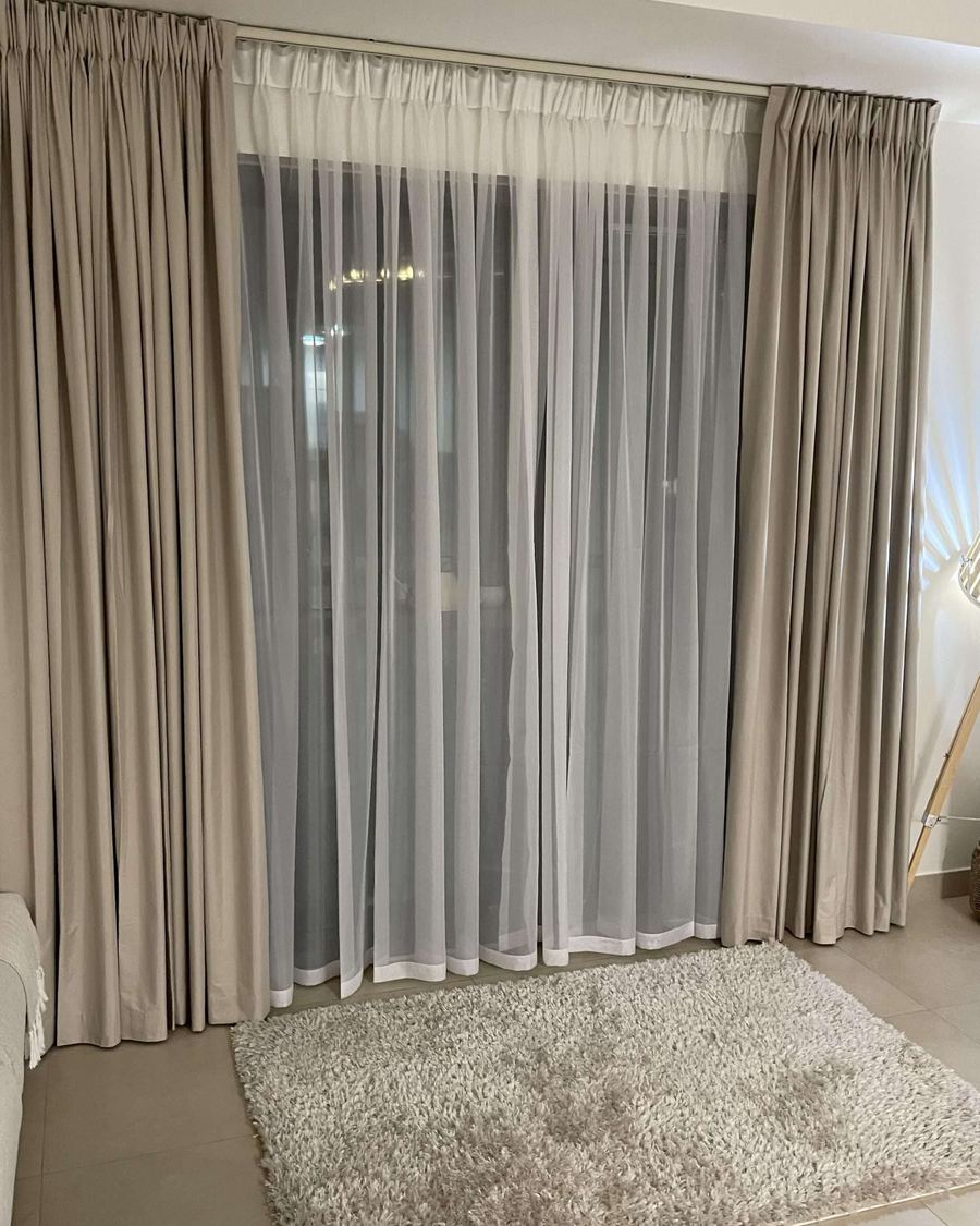 Motorized beige curtains and sheers on a wide window