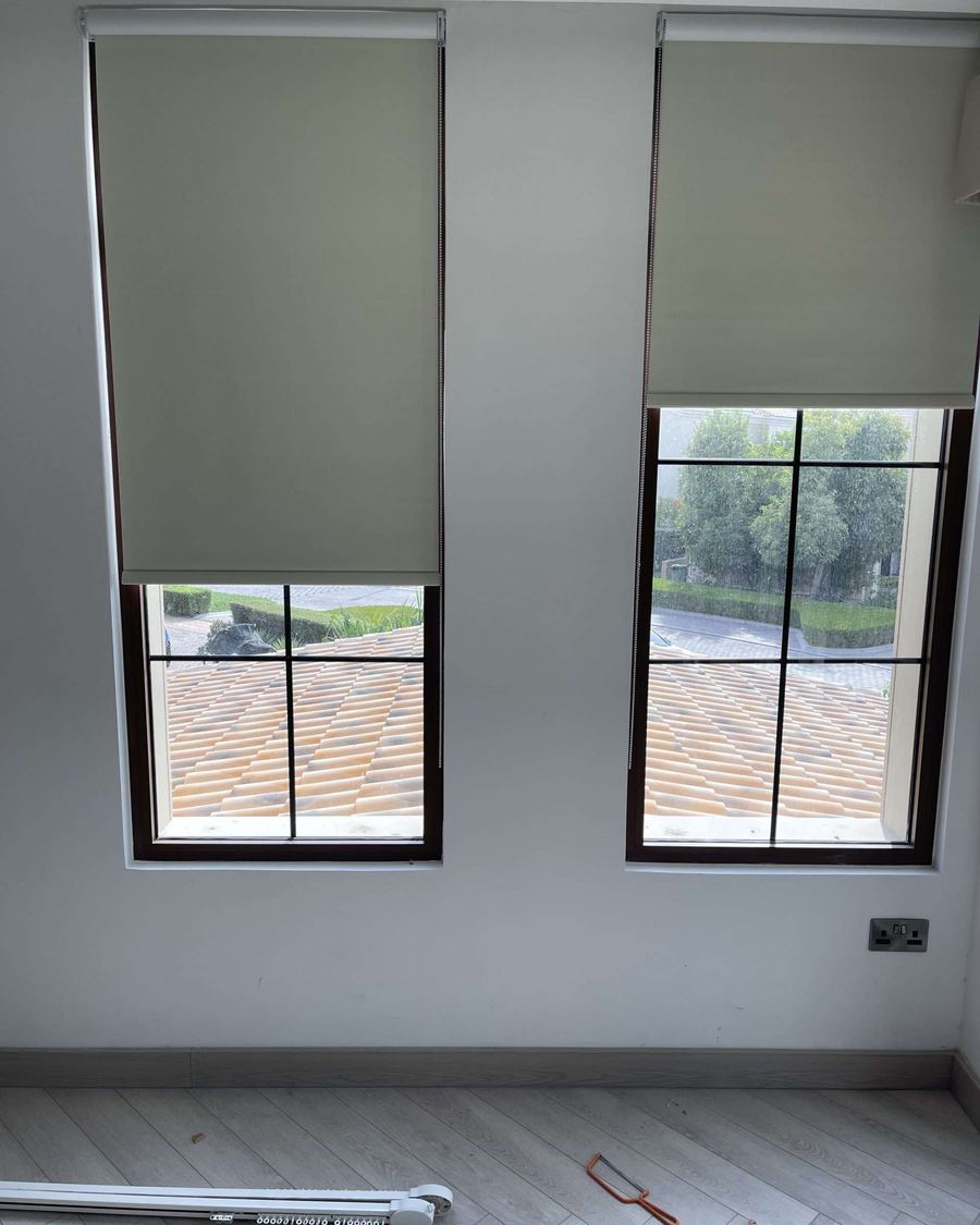 Sage green premium roller blinds on two windows in a UAE home