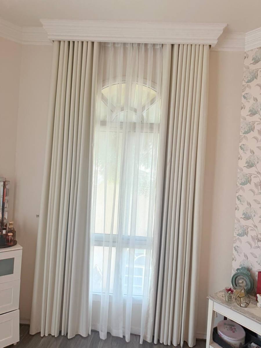 Cream curtains and sheers tailored to an arched bedroom window