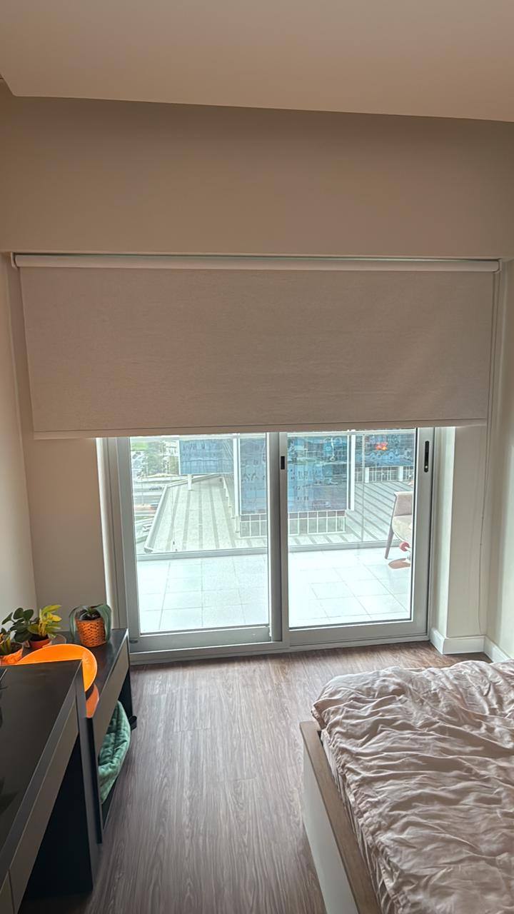 Blackout roller blind lowered over a bedroom balcony door
