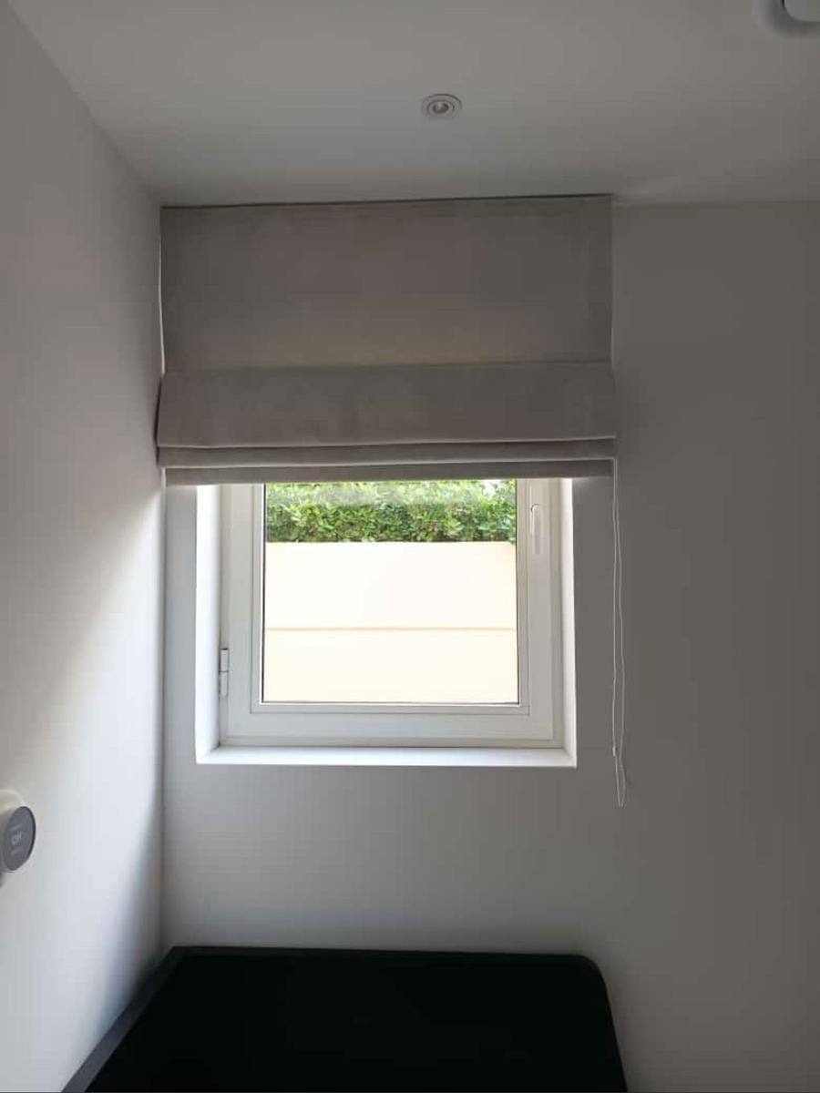 Cream roman blind on a compact guest room window