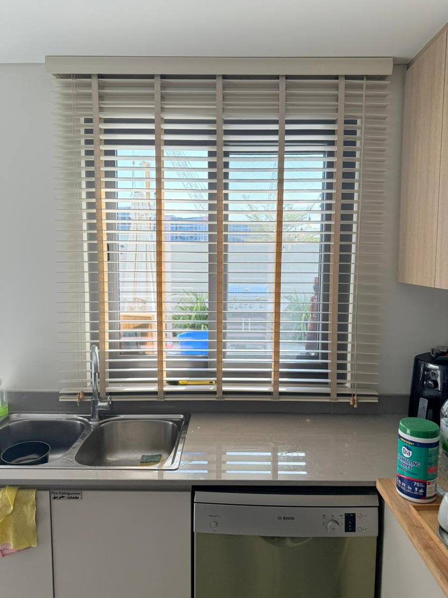 Cream wooden venetian blinds installed over a kitchen sink window