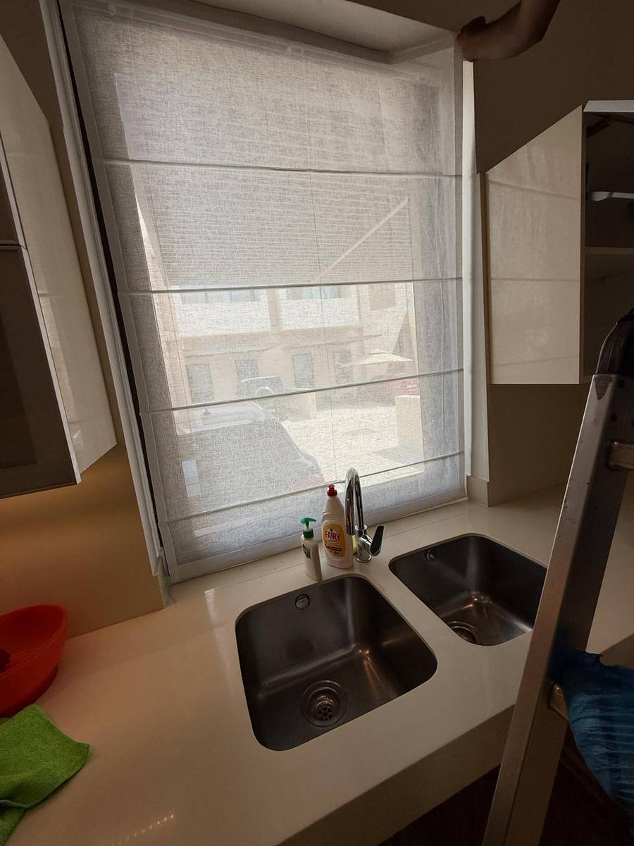 Light-filtering woven roman blind installed above twin kitchen sinks